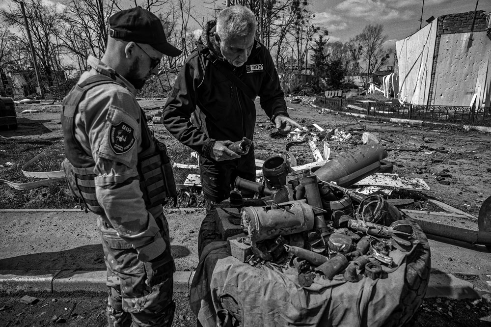 a man points to explosive hazards to warn a soldier about the danger.