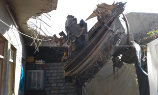 A tank turret next to a house with the barrel stuck in the ground; may have a cartridge in the chamber, West Mosul, Iraq.