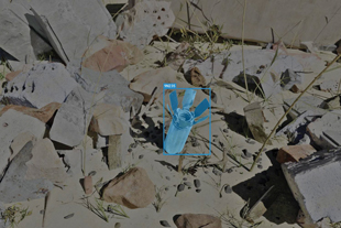 A copy of the previous image with the submunition in bright blue and the surrounding area dulled out.