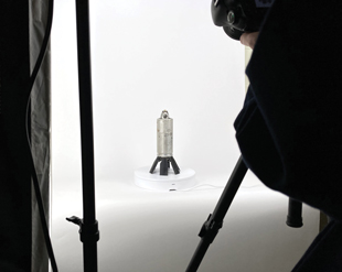 A submunition set up in front of a backdrop to be photographed