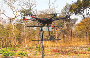 A small remote controlled drone with multiple helicopter blades above and a silver box with a Lidare muntaed on the bottome