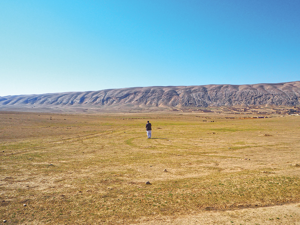 A flat plain of land with a mountain in the distance.