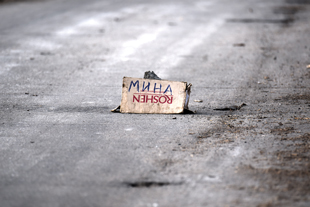 Upside down cardboard box on a road with "MINES" written in Ukrainian on the side.
