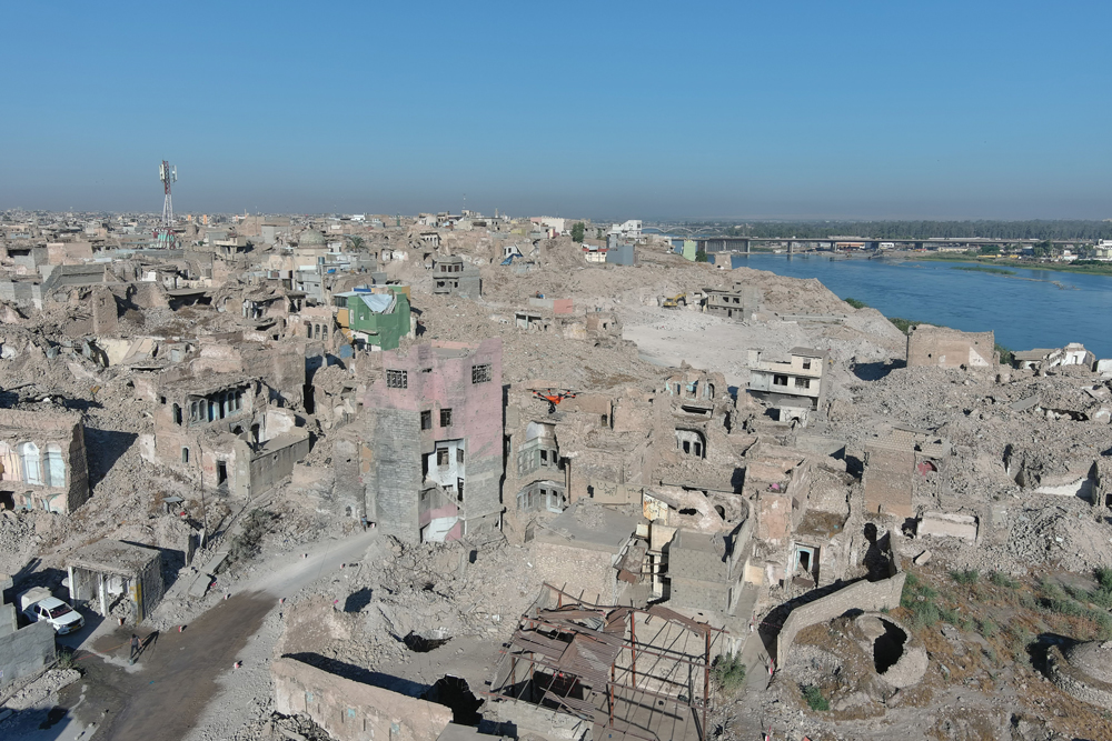 Cityscape of partially destroyed tan-colored buildings in Mosul, Iraq.
