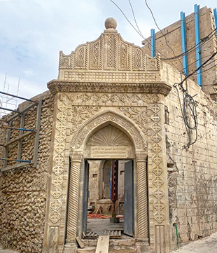 A tan-brick church with an ornate doorway.