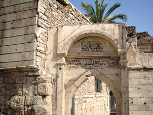 A stone archway above a door with ornate Arabic script.