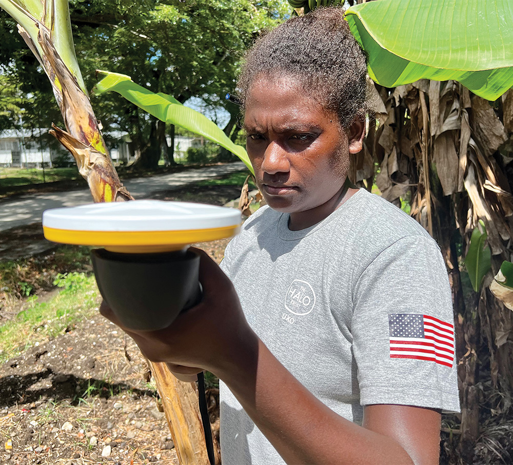 A woman in a gray shirt with a U.S. flag on the arm looks examines a yellow and white device.