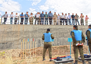 A group of people watching a demonstration to clear landmines