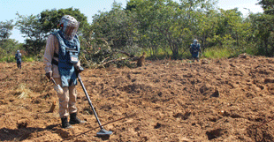 person with a metal detector in a dirt field