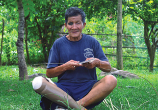A person sitting on the grass with a patch on his eye and a prosthetic leg.