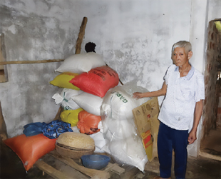 A person standing next to a pile of different colored bags stacked against a wall.