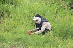 Person wearing protective gear kneels in the grass