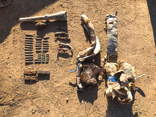 A variety of twisted metal objects laying on the dirt ground.