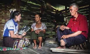 Three people sitting on the floor. One person is interviewing the other two, one of whom has a missing leg