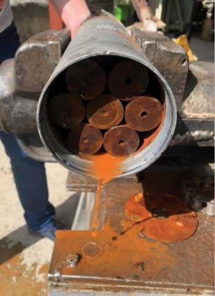 An open cylinder with rusting rods inside leaking out a rust colored liquid