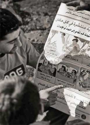 A person points to a poster with illustrations showing how to be safe around explosive ordnance