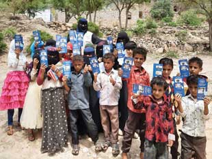 A group of children hold up brochures