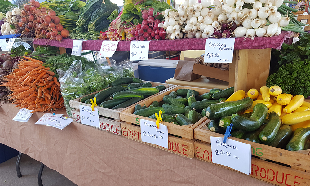 A table displaying a variety of fresh vegetables at the harrisonburg Farmers Market.