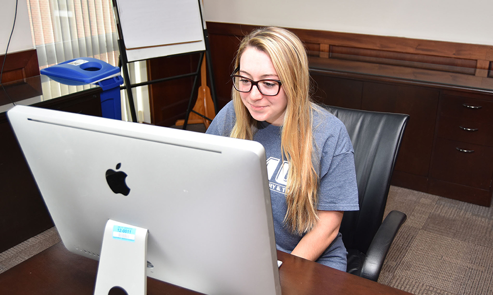 QFIN major Heather Caminske sitting at an iMac