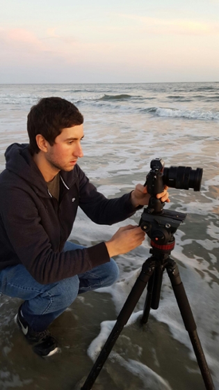 Garrett Martin setting up a tripod while on a beach photoshoot