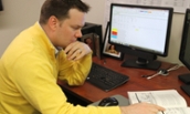 MBA Student in yellow sweater studying at a desk with book and computer