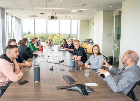The Accreditation Board for Engineering and Technology (ABET) engaged in a discussion around a conference table in a bright, modern meeting room.