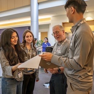 Group of colleagues in a lobby discussing papers together.