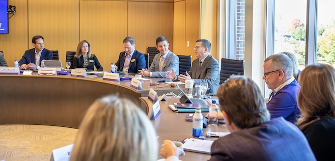 Board of Advisors roundtable discussion in a conference room with several attendees engaged in conversation.
