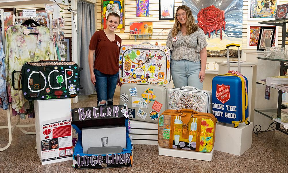 Katie Antonucci (left) and Grayson Crow (right) displayed decorated suitcases at Oasis in Downtown Harrisonburg.