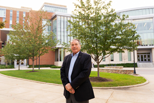 Charlie King standing in front of the College of Business Learning Complex
