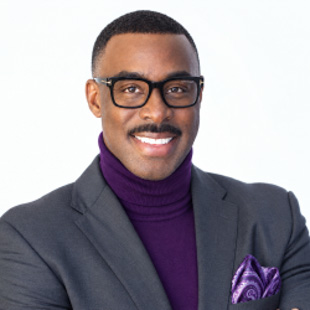 Studio headshot of Darrel Branch wearing glasses, a gray suit jacket, and a purple turtleneck with a matching pocket square.