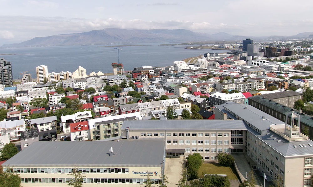 Aerial view of Reykjavík, Iceland, showcasing colorful rooftops, modern buildings, and the surrounding mountains and ocean.