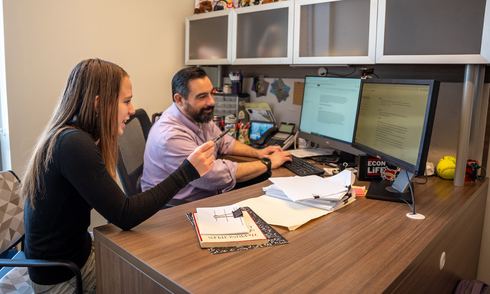 Student Lena Caffall and faculty member John Kruggel work together at a computer. 