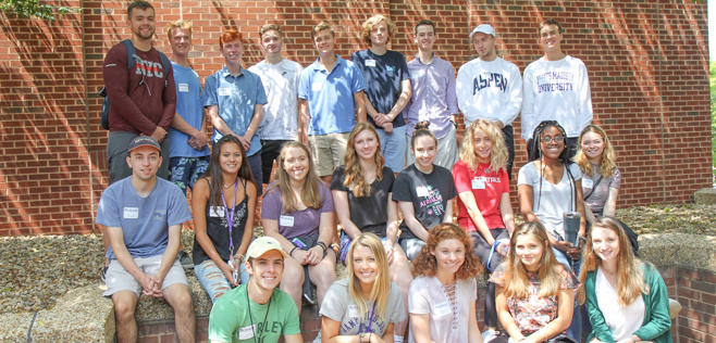 MadisonBiz students posing for a photo outdoors in front of a brick wall.