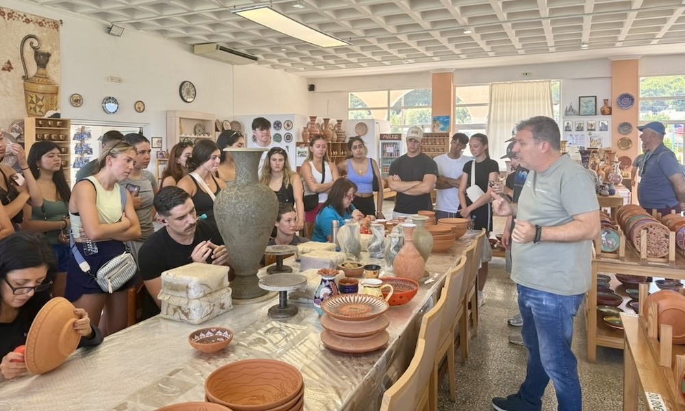 A pottery workshop where an instructor is demonstrating techniques to a group of attentive participants.