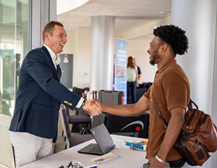 A student shaking hands with a recruiter.