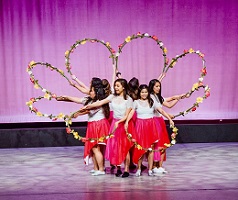 photo of women performing on stage in a circle with flower hoops