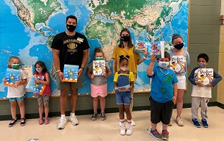 Photo of athletes with students and books