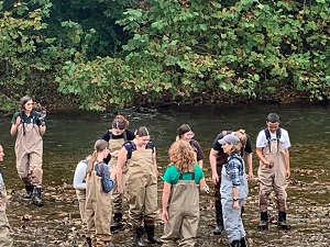 students and First Lady Northam wading in stream