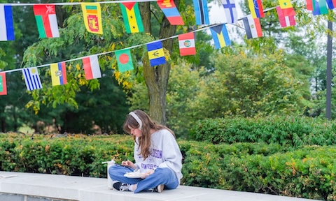 A student sitting studying surrounded by international flags hanging for International Week