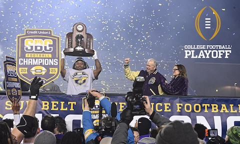 JMU football player showing the sunbelt championship trophy alongside university president