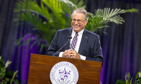 Charlie King smiling at podium while addressing faculty and staff.