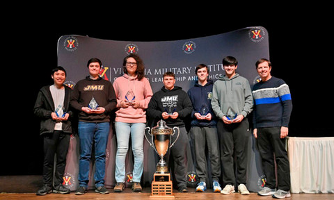 Group of students smiling and standing behind a large trophy.