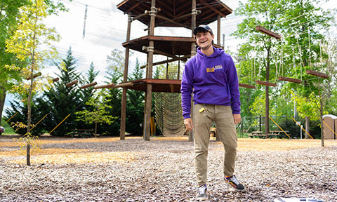 Student standing at a group challenge course outdoors