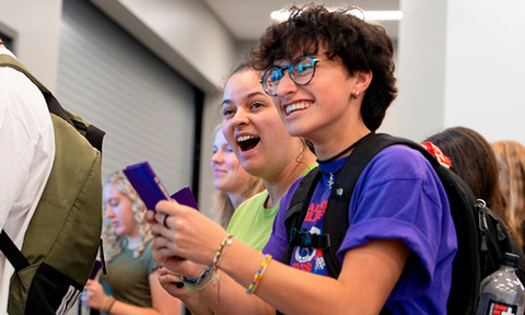 Smiling students hold purple pocket Constitution books.