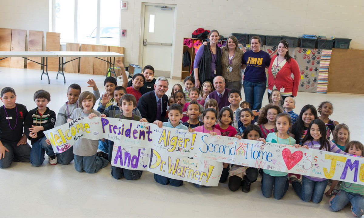 After a rousing J-M-U Duuuukes cheer the children in the after-school program, Second Home, unveil a banner to welcome President Alger and Dr. Warner.