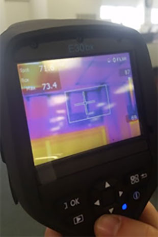 hand holding a thermal imager with a small screen filled with shades of orange and blue.