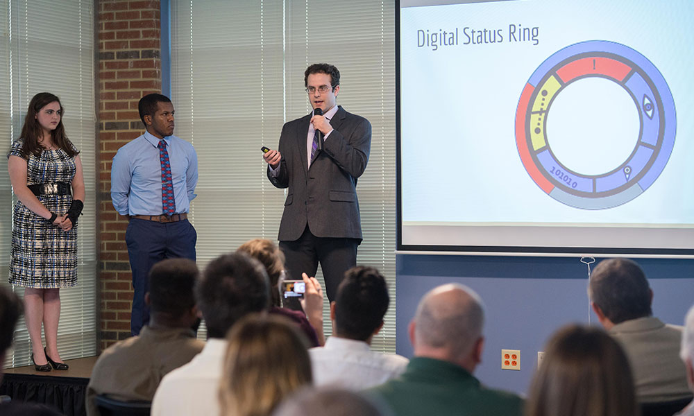 students discuss slide being shown on a screen that shows a chart with concentric circles filled with colors to represent various battlefield conditions.