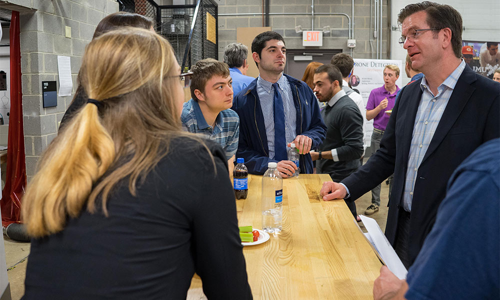 Darren Halford stands at a workbench surrounded by students.