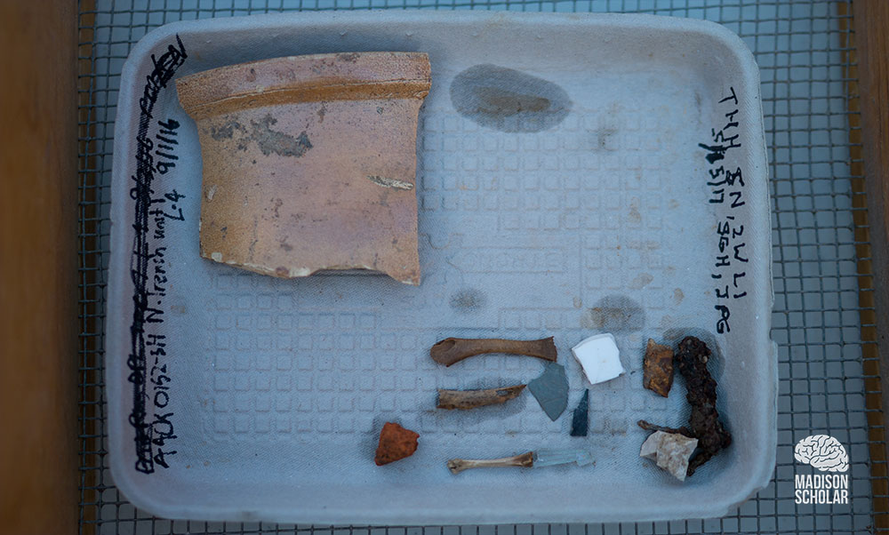 A tray holds pottery pieces and other artifacts recovered from the house.
